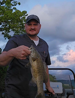 Boone McCrary with a fish on a lake at sunset