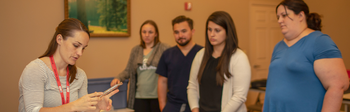 Female instructor performing a demonstration for four residents during an Advanced Trauma Life Support class