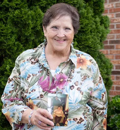 Smiling woman holding a photo showing her weight loss progress