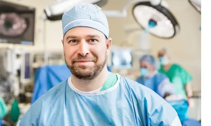 Dr. Burns in operating room wearing surgical cap, scrubs