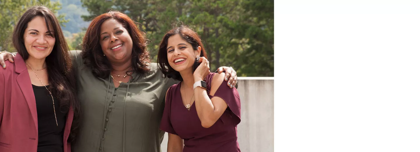 Three women smiling while standing outside