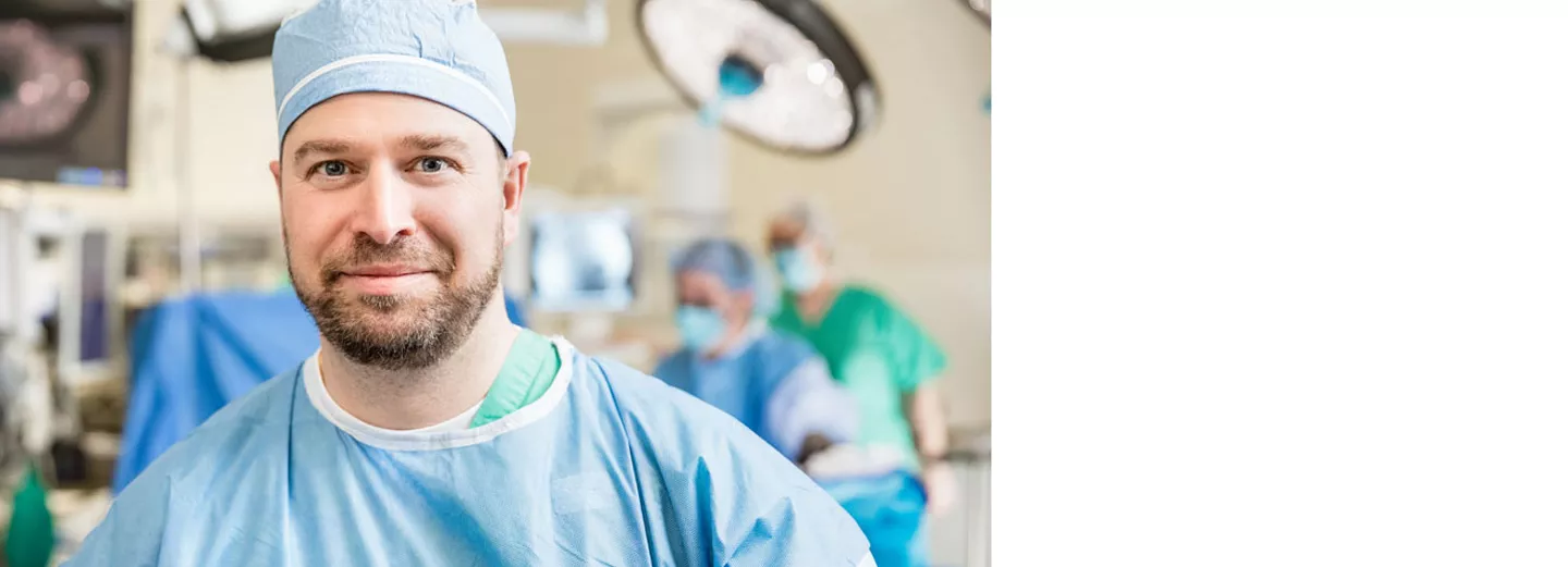 Dr. Burns in an operating room wearing a surgical cap and gown